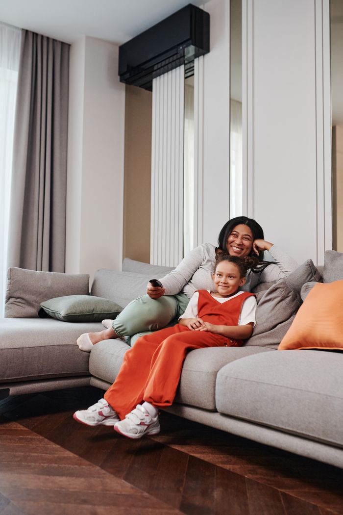 A mother and daughter enjoy a cozy moment on a modern living room sofa, sharing quality time together.