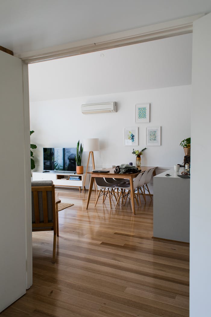 Contemporary apartment with modern chairs and table near wall decorated with pictures in daytime
